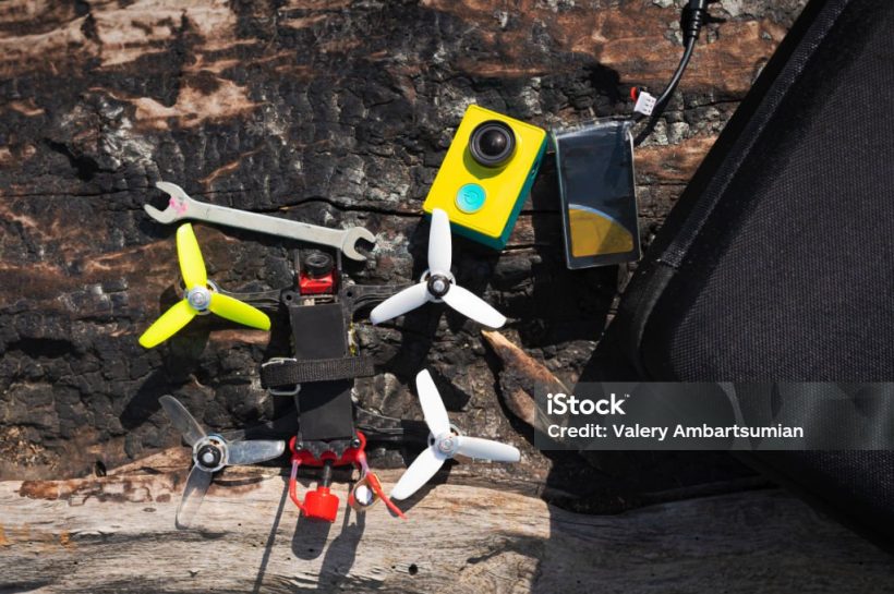 multicolored racing quadrocopter drone with tools on a log outdoors